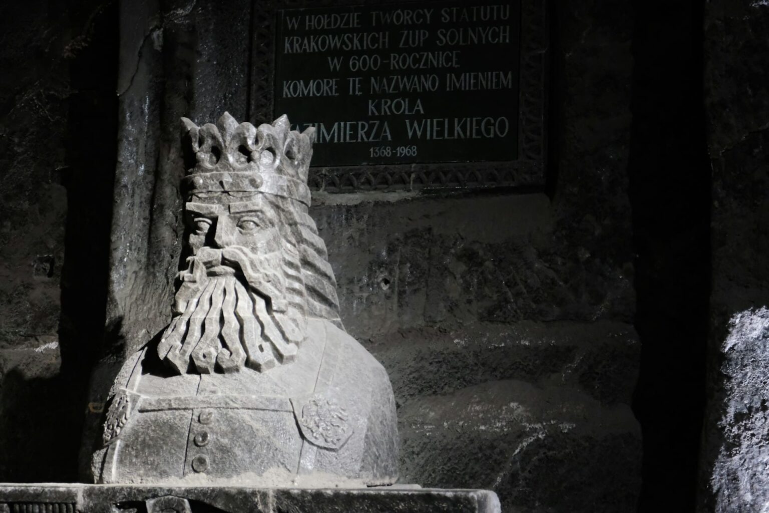 Conjunções (konjunkcioj) em esperanto Busto de pedra de um rei de coroa e barba longa, diante de uma placa em polonês em homenagem ao rei Casimiro, o Grande