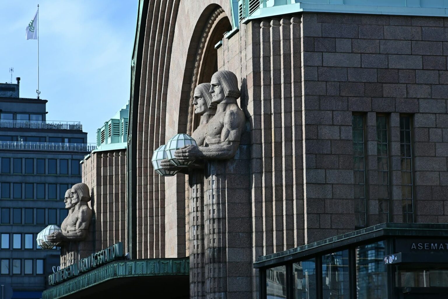 Estátuas que seguram lanternas na fachada da Estação Central de Helsinque
