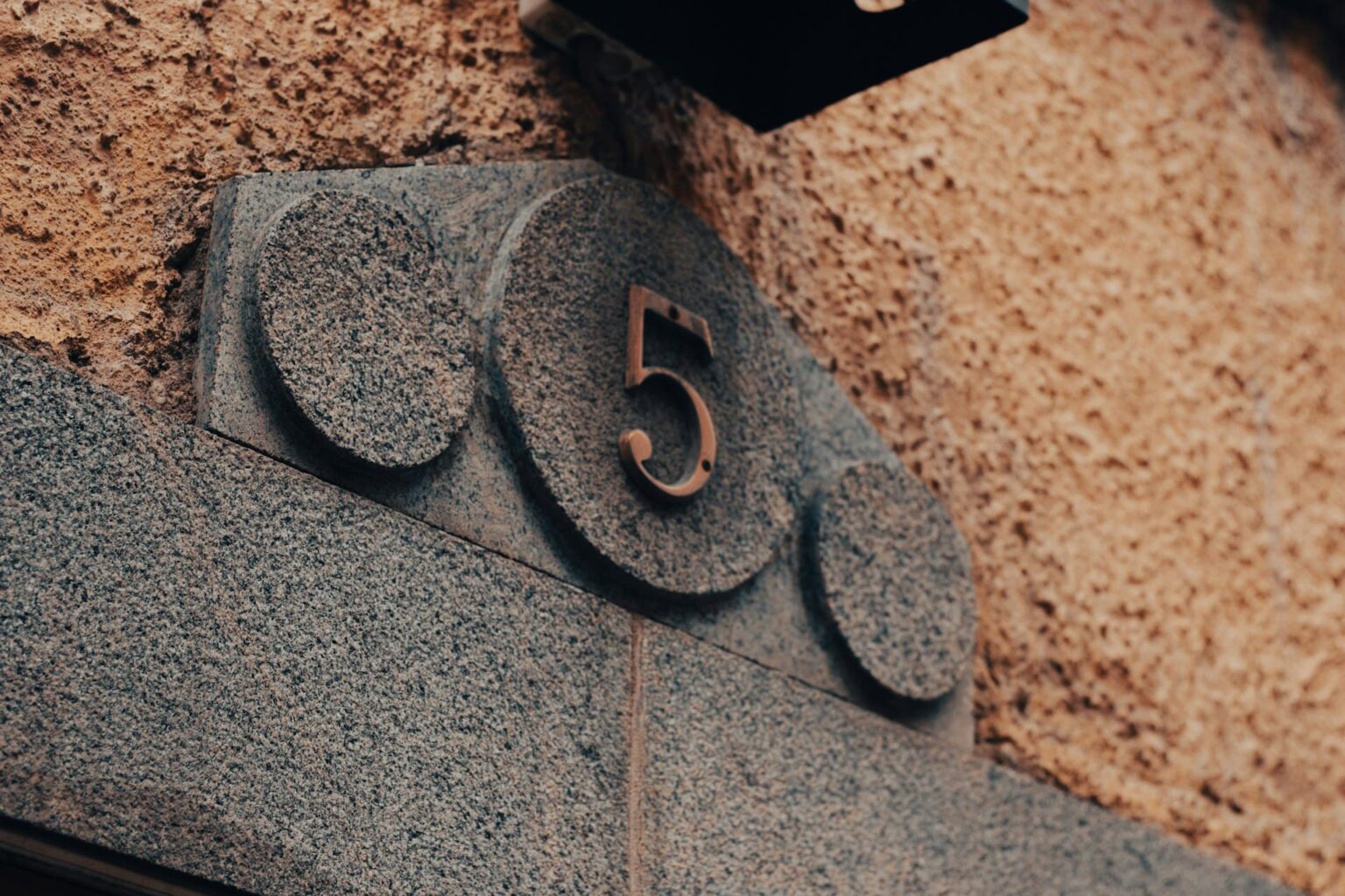 Número 5 de metal em placa de granito na fachada de um prédio