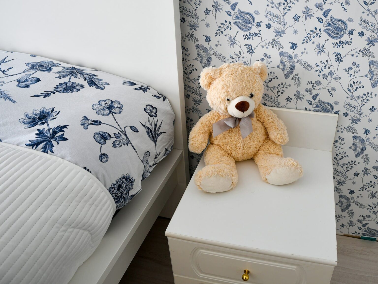 Urso de pelúcia sobre o criado-mudo, ao lado de uma cama
