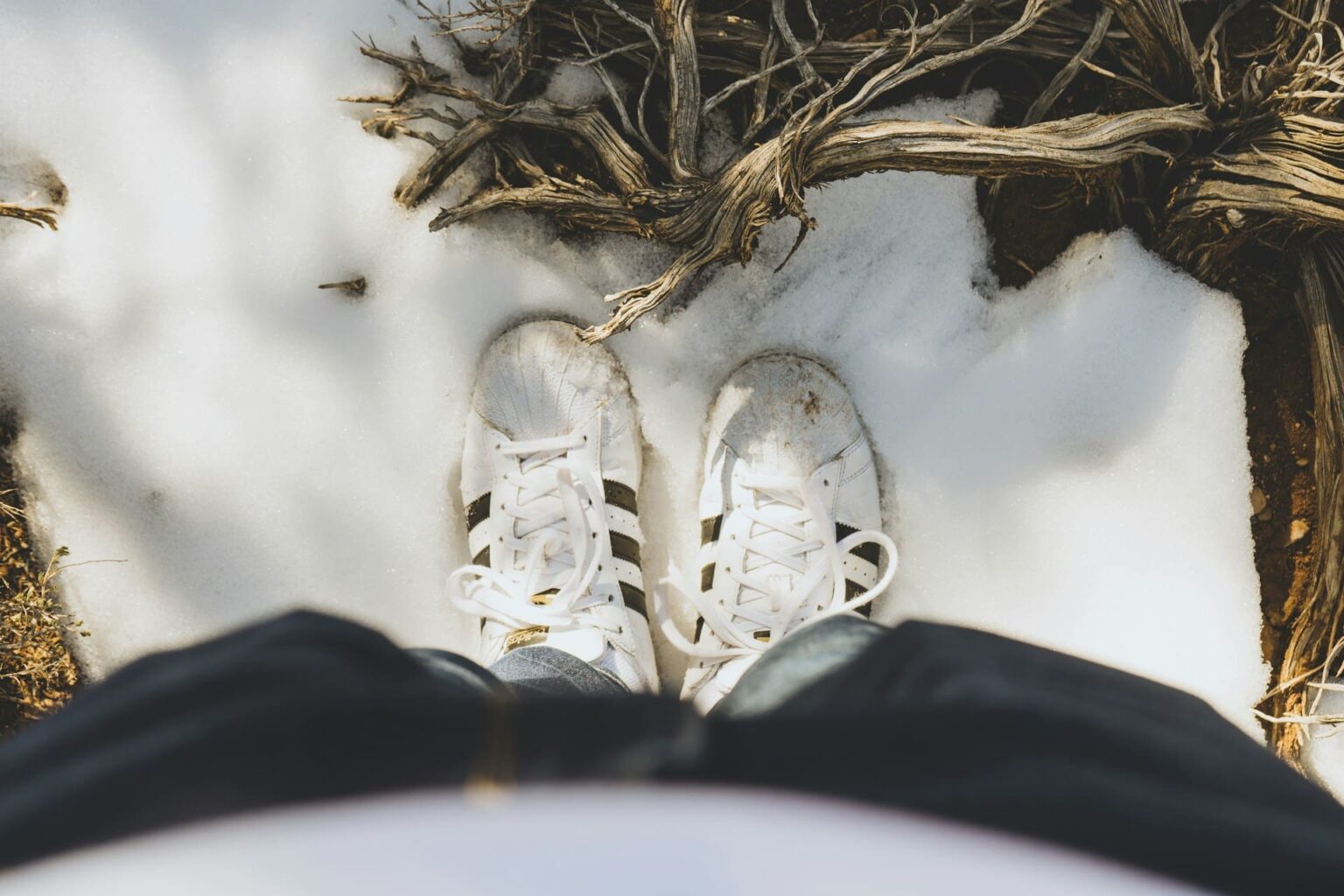 Pés com tênis brancos sobre a neve, vistos de cima