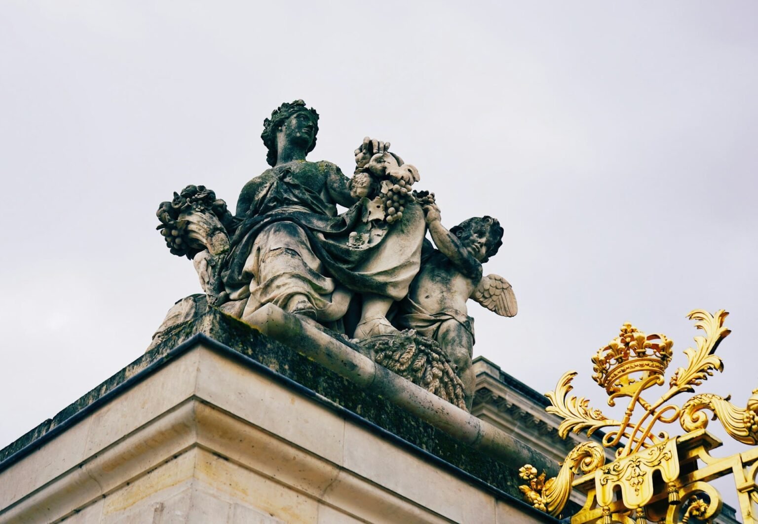 Passé composé em francês: com avoir ou être Estátua de mármore de uma mulher ajoelhada em oração numa galeria com bustos