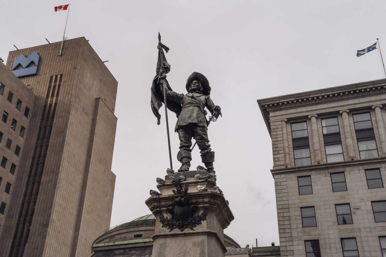 Francês do Québec: história, pronúncia e vocabulário Monumento a Maisonneuve na Place d'Armes, em Montreal, com as bandeiras do Canadá e do Québec