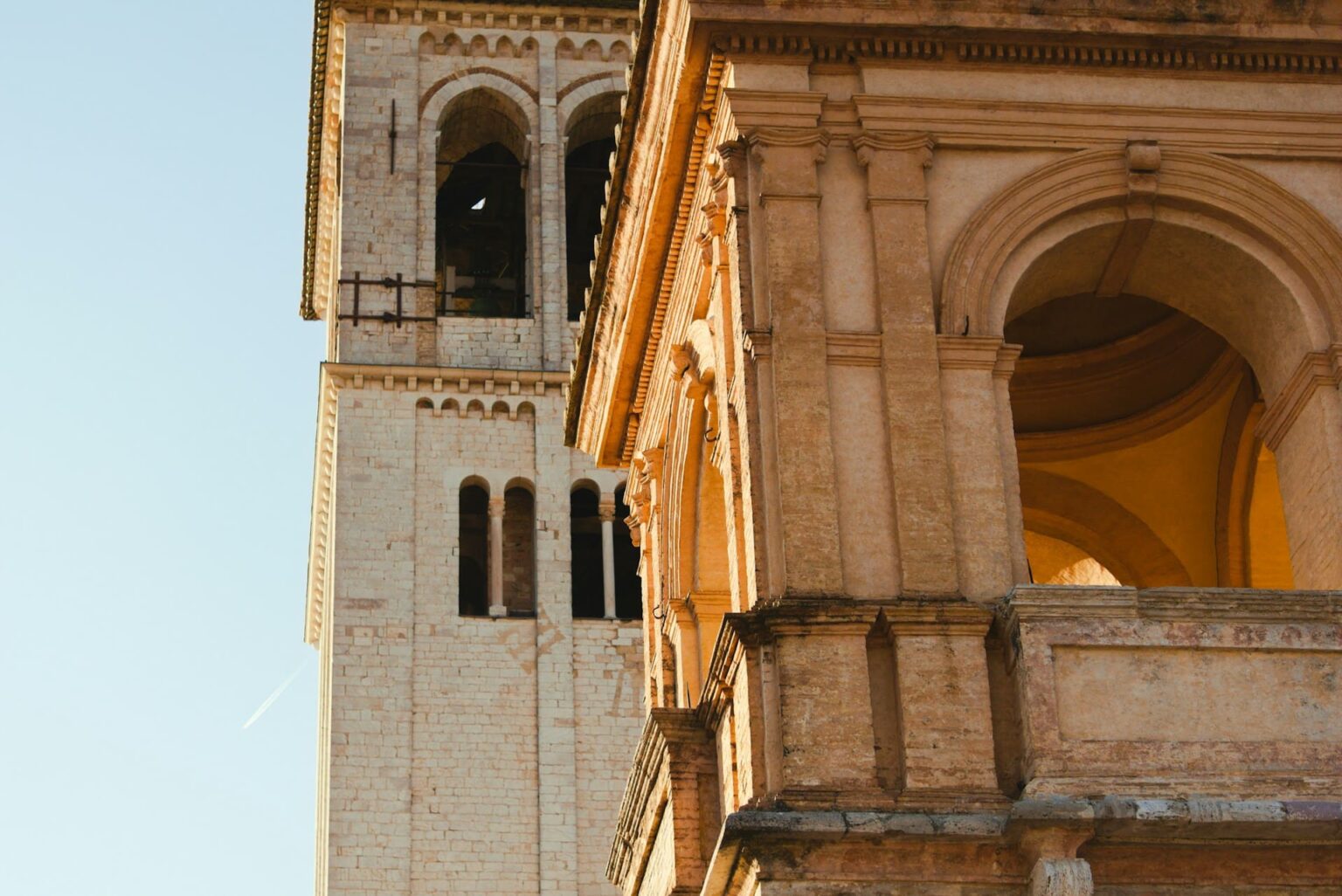 Tempos verbais em italiano: quando usar cada um Campanário e fachada de uma igreja de pedra clara iluminados pelo sol