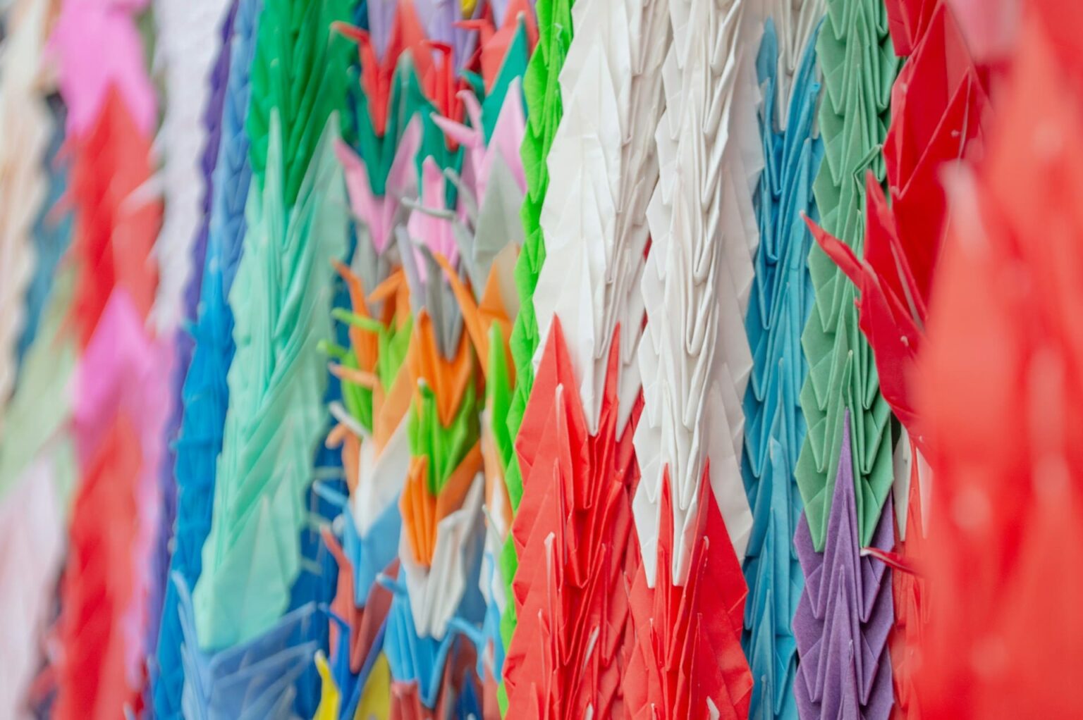 Fileiras de tsurus de origami em papel vermelho, branco, verde, azul e roxo