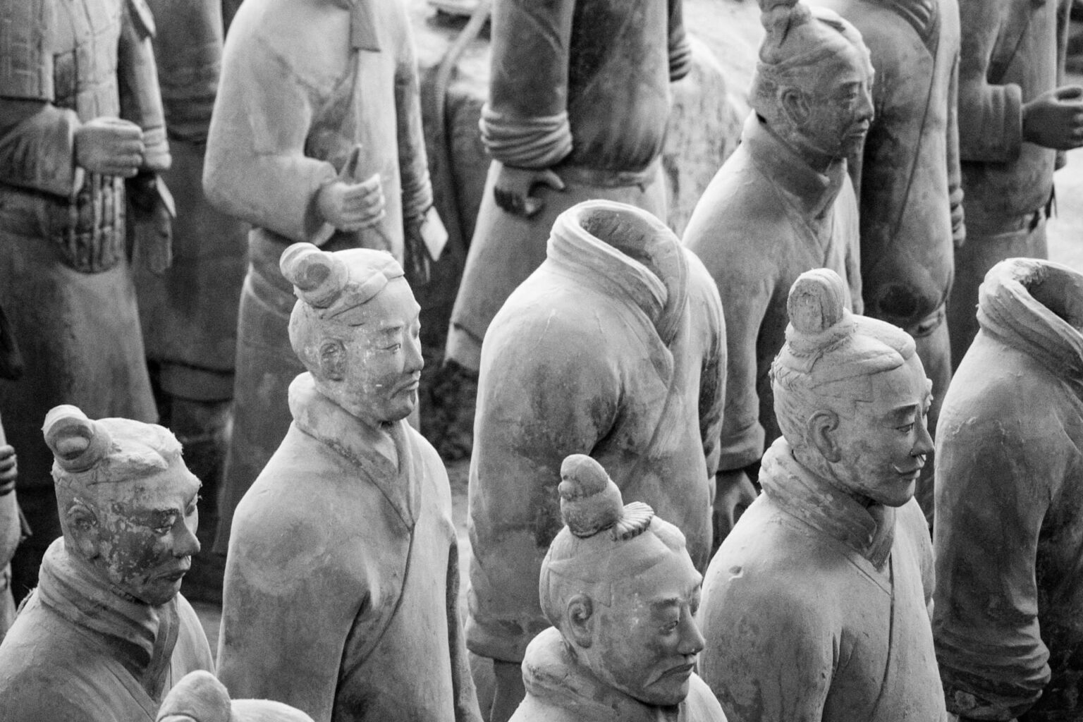 Guerreiros de terracota enfileirados em preto e branco, alguns sem cabeça