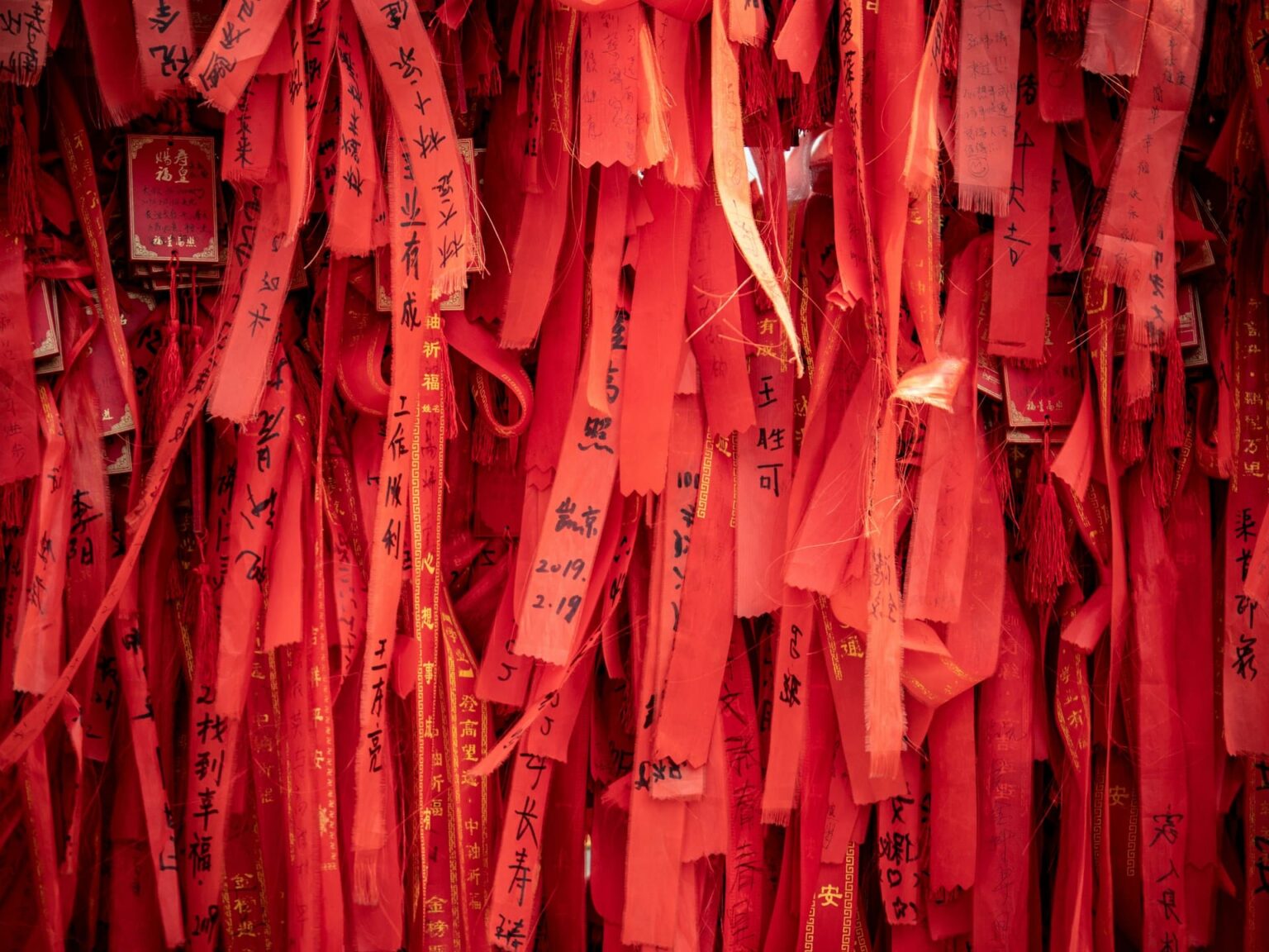 Fitas vermelhas com desejos escritos à mão em caracteres chineses, penduradas lado a lado