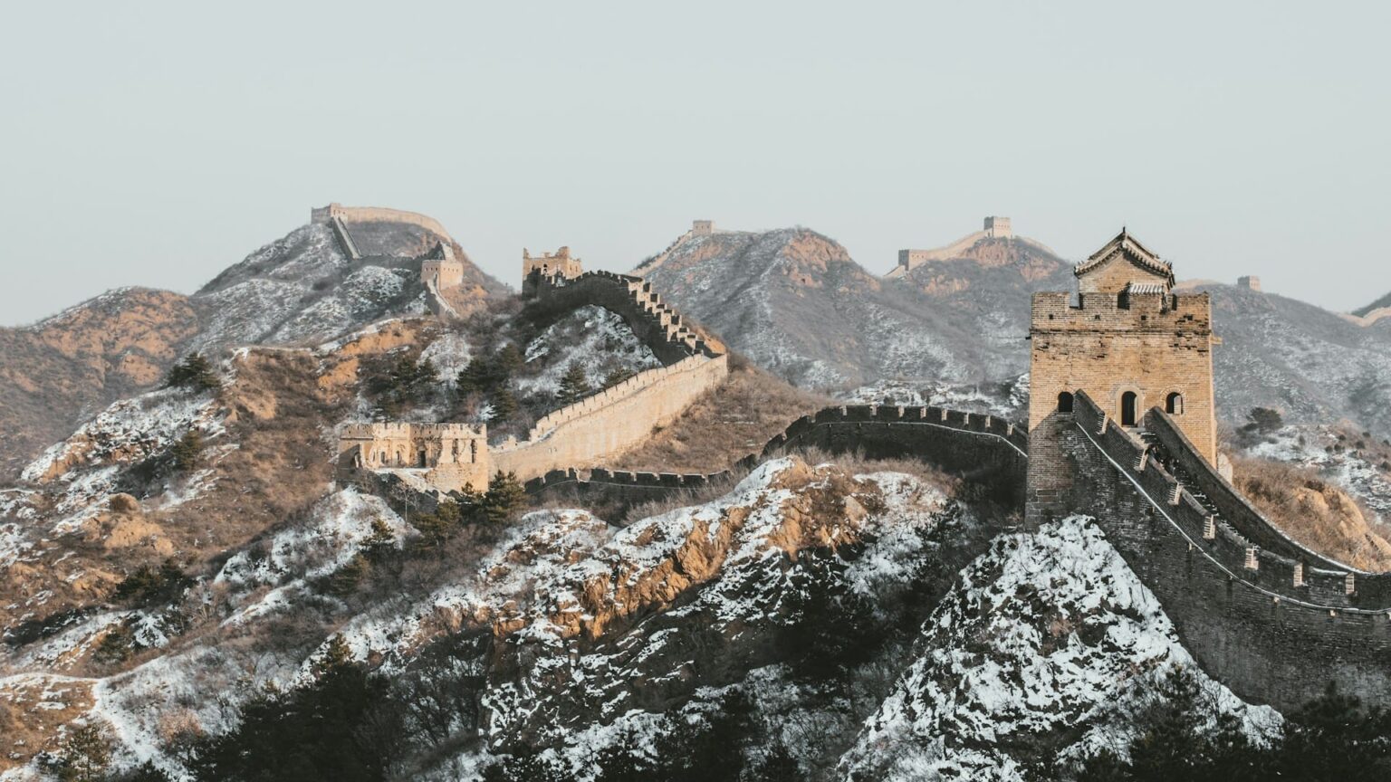 Trecho da Muralha da China com torres de vigia sobre montanhas cobertas de neve