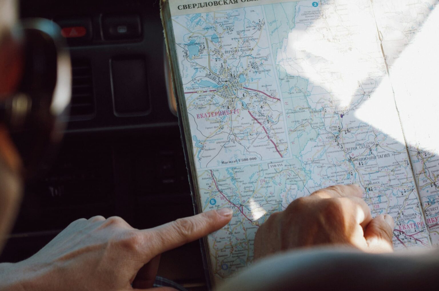 Mãos apontando um mapa rodoviário em russo da região de Sverdlovsk, com Ecaterimburgo em destaque