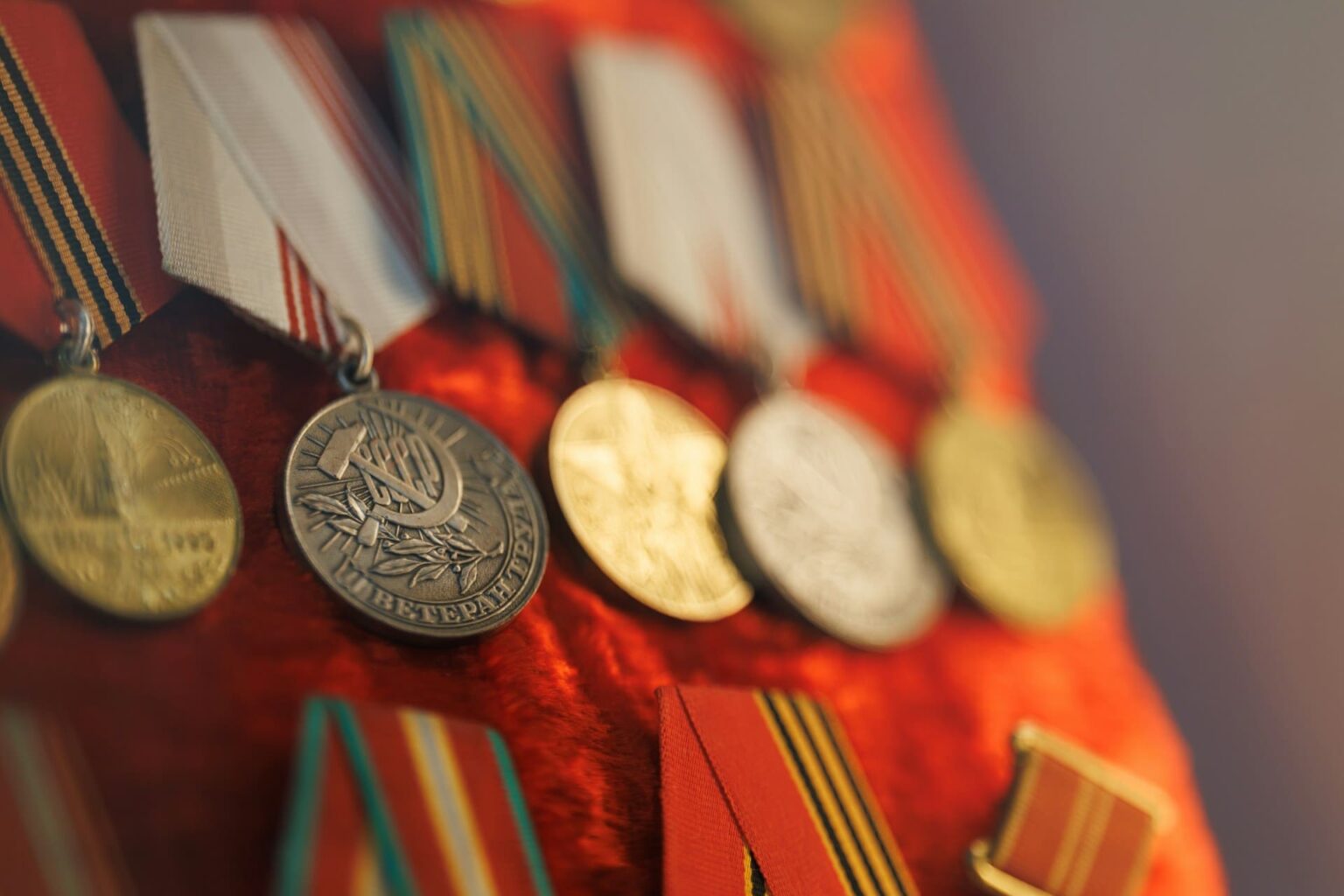 Medalhas soviéticas com fitas listradas de laranja e preto, presas num tecido vermelho
