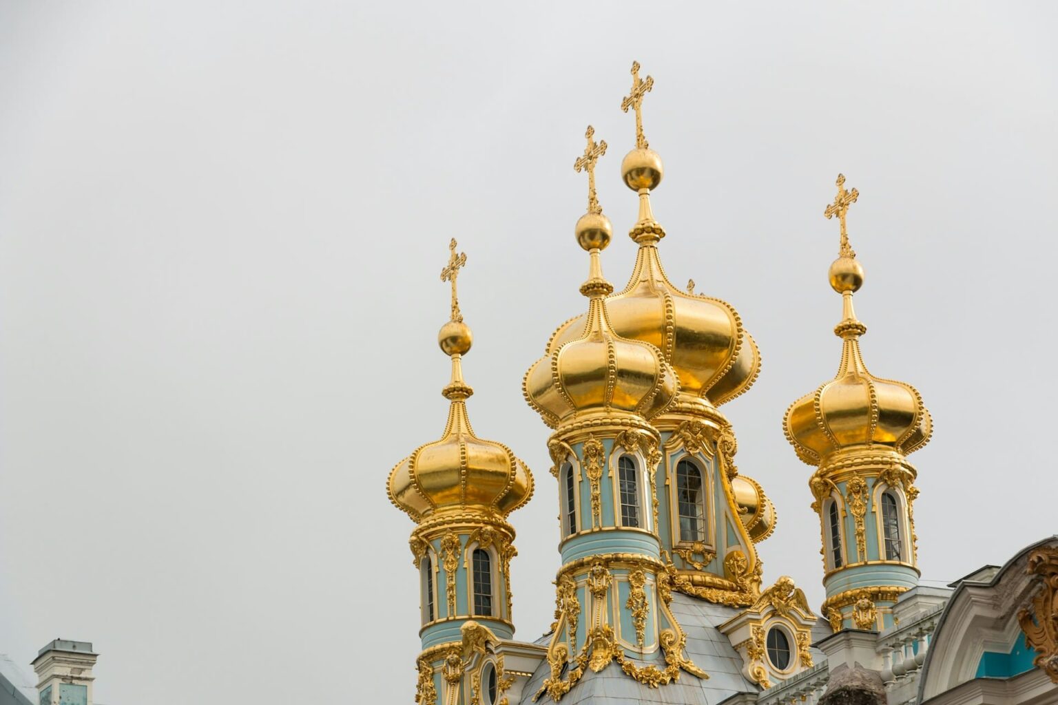 Cúpulas douradas em forma de bulbo de uma igreja ortodoxa, com paredes azul-claras e cruzes no alto