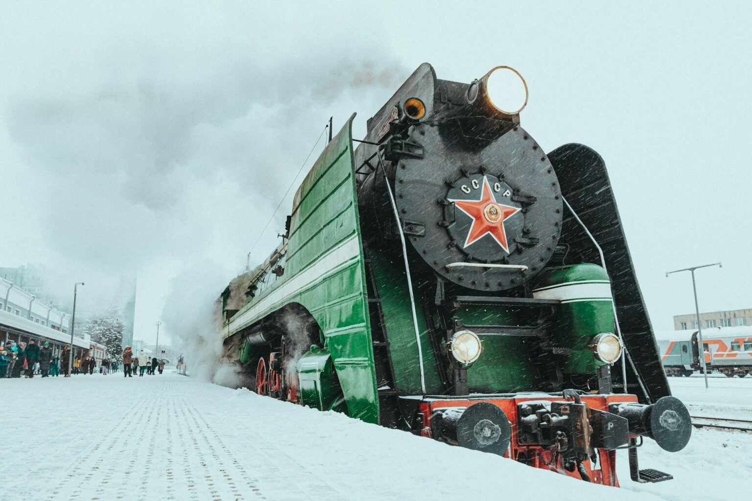 Verbos (глаголы) em russo: passado, futuro e aspecto Locomotiva a vapor soviética, com a estrela vermelha e a inscrição СССР, soltando fumaça sob a neve