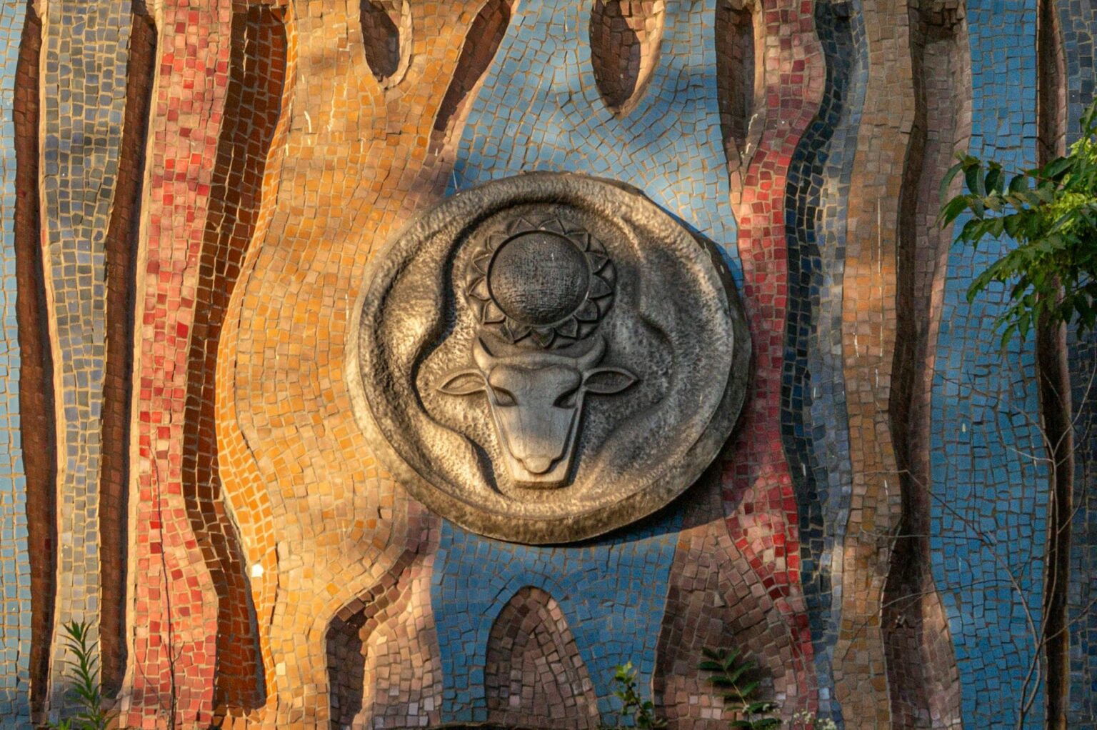 Mosaico colorido com um medalhão em relevo de uma cabeça de touro sob um sol
