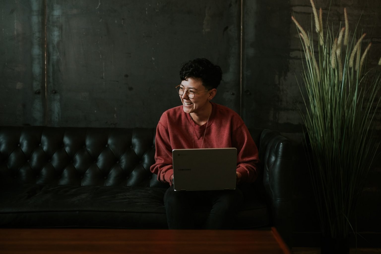 5 razões para aprender uma nova língua ainda este ano Mulher sentada em um sofá segurando um notebook